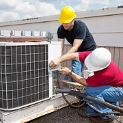 Two repairmen working on an HVAC system repair